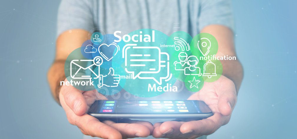 Businessman holding a cloud of social media network icon Person holding a cellphone with social network concept popping out in a cloud.